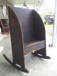 a wooden chair sitting on top of a cement floor next to a metal pole and door