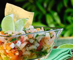 a glass bowl filled with mexican food and garnished with lime wedges on top