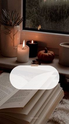 an open book sitting on top of a table next to candles