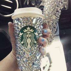 a woman holding up a starbucks cup with lots of diamonds on it's wrapper