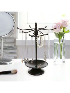 a jewelry holder with necklaces hanging from it's sides on a table next to a flower vase