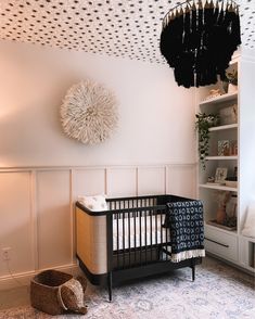 a baby crib in the corner of a room with a chandelier above it