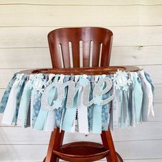 a wooden chair sitting on top of a table covered in blue and white fabric ruffles