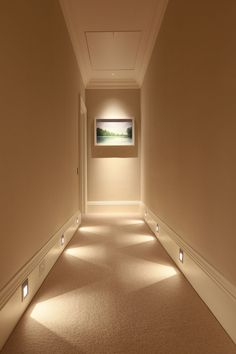 an empty hallway with lights on the walls and carpeted floor in front of it