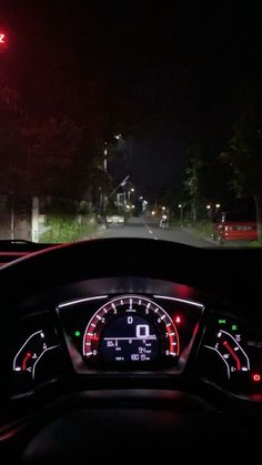 the dashboard of a car is lit up at night with red and green lights on