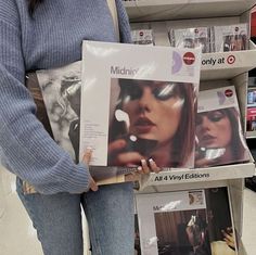 a woman holding up an album in a store