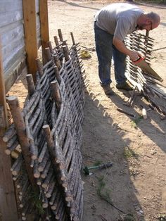 a man is bending over to pick up something from the ground next to a fence