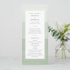 a white and green wedding program on a table next to a vase with flowers in it