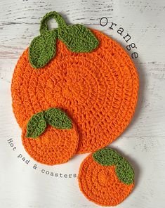 an orange crocheted coaster with green leaves