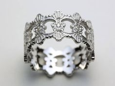 a white gold and diamond ring with filigrees in the middle, on a gray background