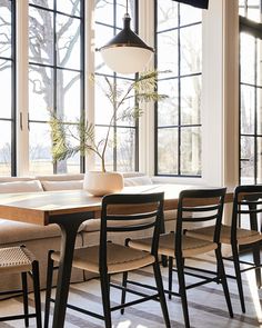 a living room filled with furniture and lots of windows next to a wooden dining table