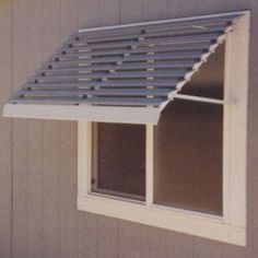 a small window with a metal roof on the side of a building