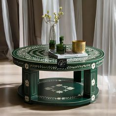 a green table with flowers and books on it in front of white drapes curtains