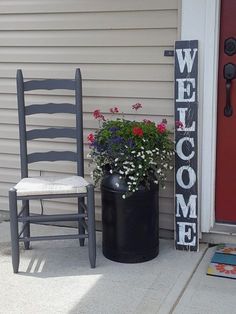 a welcome sign next to a chair and potted plant on the front porch with flowers in it