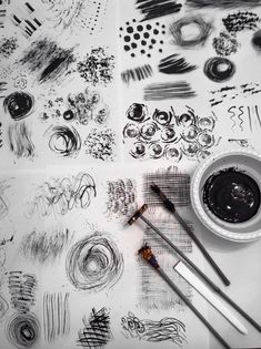 a table topped with lots of different types of ink and paintbrushes on top of paper