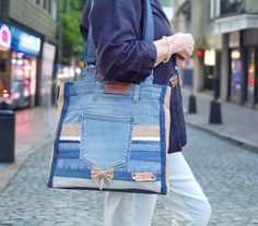 a woman walking down the street carrying a blue bag with pockets and bows on it