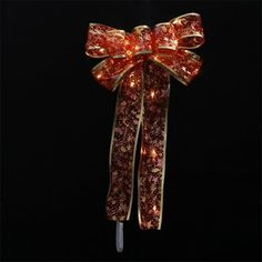 a red and gold bow with lights on it's side hanging from a hook