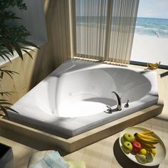 a bath tub sitting on top of a wooden floor next to a bowl of fruit