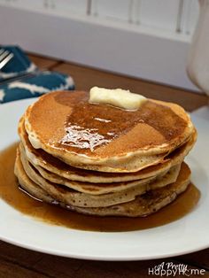 stack of pancakes with syrup and butter on white plate