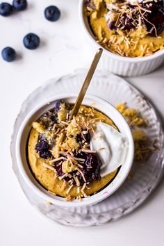 two bowls of oatmeal with blueberries and whipped cream on the side