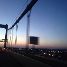 a view from the back of a car driving over a bridge at night with city lights in the background