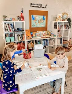 two children sitting at a table with books in front of them and an american flag on the wall