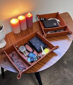 two wooden trays filled with various items on top of a table next to candles