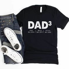 a t - shirt that says dad 3 and is next to two pairs of jeans