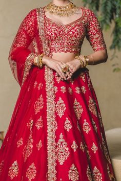 a woman in a red lehenga with gold jewelry on her neck and shoulders