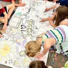 several children sitting around a large sign with writing on it