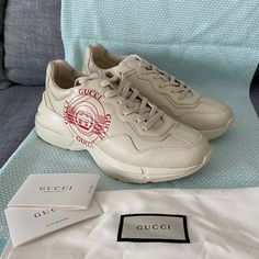 These Are A Brand New Authentic Pair Of Gucci Rhyton Sneakers. A Reference To Retro Sportswear, The Rhyton Sneaker Stands Out For Its Chunky Silhouette And Oversize Sole. Features A Leather Upper Body And A Rubber Sole In Ivory. Made In Italy. Original Box, Dust Bag And Tags Included. Luxury Gucci Sneakers, Designer Sneakers With Logo Detail And Round Toe, Designer Gucci Sneakers With Logo Print, Luxury Gucci Sneakers With Embroidered Logo, Gucci Custom Lace-up Logo Sneakers, Gucci Sporty Custom Sneakers With Logo, Gucci Custom Logo Sporty Sneakers, Sporty Gucci Custom Sneakers With Logo, Gucci Designer Sneakers With Embroidered Logo