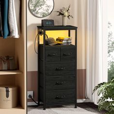 a black chest of drawers sitting next to a mirror and plant in a room with beige walls