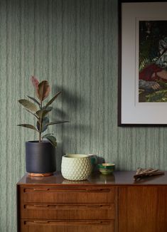 two planters sit on top of a dresser in front of a wallpapered background