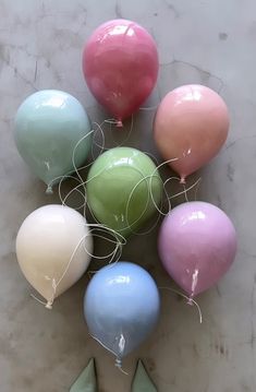 several balloons with string attached to them sitting on the floor next to each other in different colors