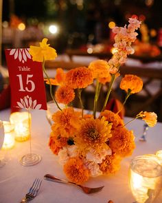 an arrangement of flowers and candles on a table at a wedding or other function in the evening