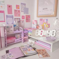 there is a large clock on the desk next to many books and toys in this room