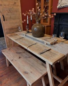 a wooden table with two benches in front of it and wine glasses on the table