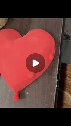 a red heart shaped cake sitting on top of a wooden table next to doughnuts