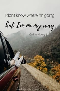 a person's feet sticking out the window of a car with mountains in the background