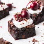 some brownies with cherries and whipped cream on top