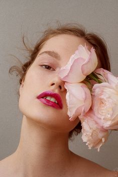 a woman with pink lipstick and flowers in her hair is looking at the camera while she holds