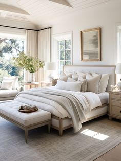 a large white bed sitting in a bedroom next to two couches and a window