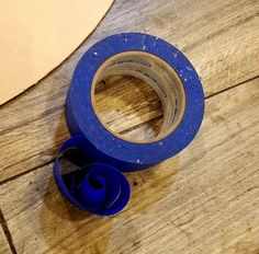 a roll of blue tape sitting on top of a wooden floor