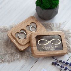 two wedding rings are placed in a wooden ring box next to a potted plant