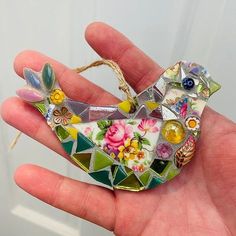 a hand holding a glass bird ornament in it's left hand,