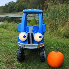 a blue toy truck sitting next to a pumpkin