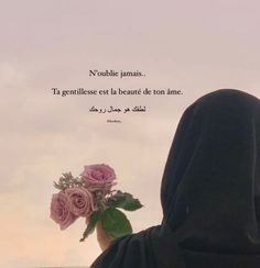 a person in a black hoodie holding a bouquet of flowers with a sky background