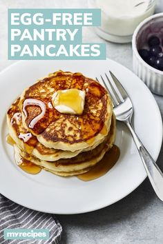 egg - free pancakes with butter and syrup on a white plate next to blueberries