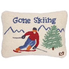 a pillow with a skier on it that says gone skiing and a pine tree in the background