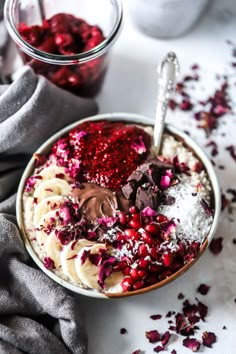 a bowl filled with chocolate, bananas and cranberries next to a cup of cocoa